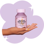 Hand holding a bottle of 'lemme IMMUNITY' daily wellness gummies against a light purple background