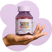 Hand holding a bottle of 'lemme MULTI' women's daily gummies against a purple heart-shaped background