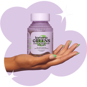 Hand holding a bottle of 'lemme GREENS' daily superfood gummies against a purple background